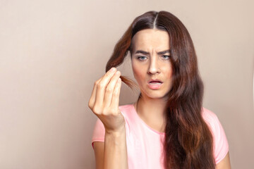 Woman has cropped, cut, weakened hair. She looks at the split ends of her hair and doesn't like...