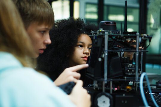 Two young students work intently on a robotics project in a modern tech lab, showcasing STEM education, teamwork, and curiosity through hands-on learning with wires and mechanical parts.