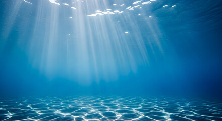 Sunlight streams through ocean water creating a serene underwater scene with a sandy bottom and a tranquil, blue atmosphere