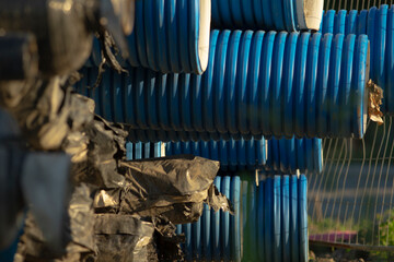 A collection of blue pipes has been arranged and neatly stacked on top of one another in a...