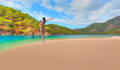 Happy slim girl in red and black bikini  with raised up arms on the seashore  - Oludeniz...