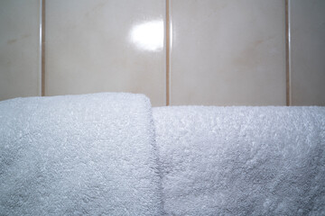 White towels hanging in front of tiled bathroom wall