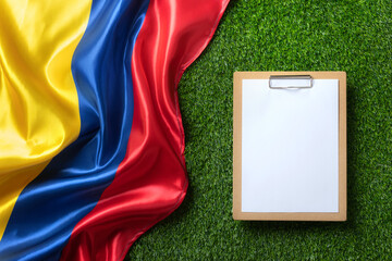 A clipboard with empty paper sheet on a green field with a Colombian flag symbolizing strategy and...