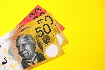 Few modern Australian dollar bills in different denominations lies on bright yellow background