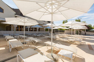 Rows of sunbeds with umbrellas in front of the hotel pool
