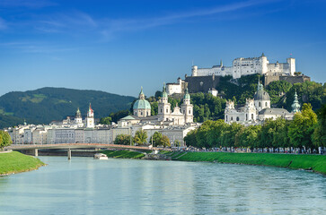 Obraz premium Salzburg, festival city in Austria. Iconic view of the old town on Salzach River, with Baroque Salzburg Cathedral in the middle, Collegiate Church to the right, and Hohensalzburg Fortress in the back.