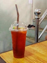 Tea mixed with honey and put in a plastic cup on the table.