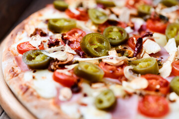 Pizza with ham, cherry tomatoes and mozzarella cheese. Wooden background. Soft focus. Close up.