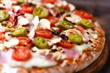 Pizza with ham, cherry tomatoes and mozzarella cheese. Wooden background. Soft focus. Close up.	