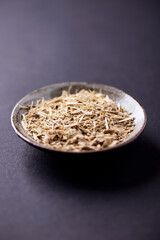 Dry Siberian ginseng (Eleutherococcus senticosus) on dark paper background. Close up.	