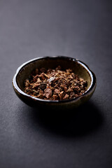 Dry root of Rhodiola rosea. Golden root, rose root. Healthy medical plant on dark paper background. Close up. Copy space.	