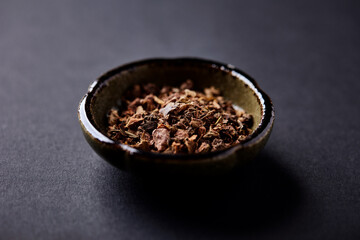 Dry root of Rhodiola rosea. Golden root, rose root. Healthy medical plant on dark paper background. Close up. Copy space.