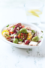 Salad with tuna, green olives and cherry tomatoes. Bright wooden background. Close up. Copy space.	