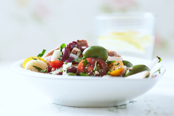 Salad with tuna, green olives and cherry tomatoes. Bright wooden background. Close up. Copy space.