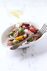 Salad with tuna, green olives and cherry tomatoes. Bright wooden background. Close up. Copy space.	