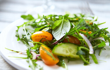 Salad with Tomatoes, Cucumber and Rocket on bright Background. Healthy Snack Idea. Close up.
