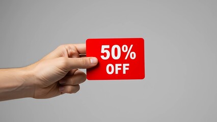 A hand holds a bright red tag labeled “50% OFF”, offering customers an attractive half-price discount for a limited-time promotion.