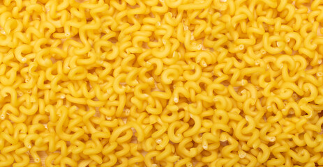 Raw yellow cavatappi pasta texture background top view. Pile of dry uncooked noodles pattern