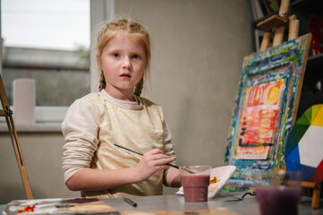 Girl enjoys painting in workshop. Art lesson. Education and learning concept. Child draw a picture...