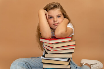 Education and school concept. Portrait of a pensive little schoolgirl leaning on a pile of books...