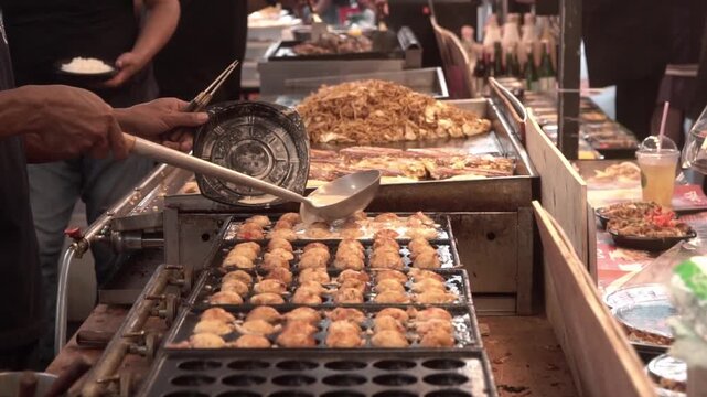 Chef hand pick up Japanese snack food takoyaki from takoyaki pan.  Cooking assorted traditional Japanese meat ball.