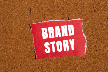 Brand story message written on ripped torn red paper piece on brown background. Conceptual brand...