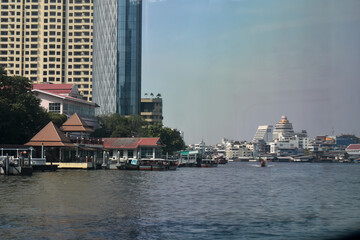 River view of Bangkok city with traditional Thai houses and modern skyscrapers contrasting against...