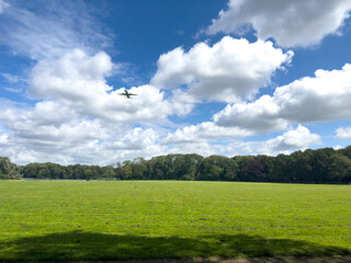 A silhouette of an airplane flying across a dramatic sky filled with large, grey clouds, symbolizing travel, aviation, and the vastness of the atmosphere.