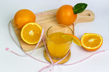 Fresh orange juice on cutting board surrounded by tape measure embodies diet wellness nutrition concept promoting healthy eating habits for weight management and vitality boosting the immune system