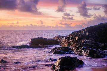 Pink sunset at the beach with waves and coast rock