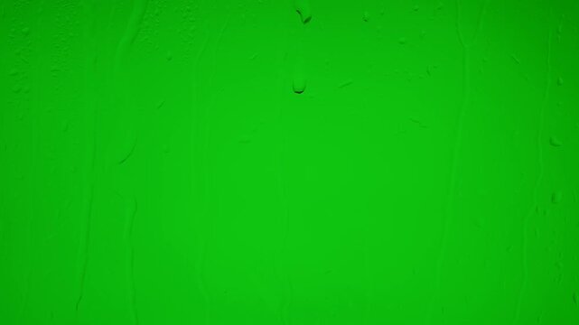 Wet glass surface with raindrops on green chroma key background
