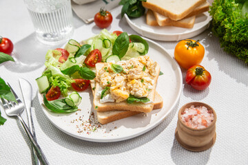 Scrambled eggs on toast bread with cucumber, tomato and herbs.White background.Healthy breakfast