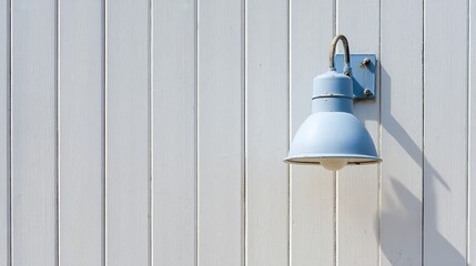 Close-up of an exterior wall with light blue and white vertical paneling, featuring an industrial-style outdoor lamp hanging on the side