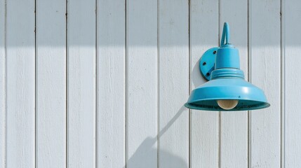 Close-up of an exterior wall with light blue and white vertical paneling, featuring an industrial-style outdoor lamp hanging on the side