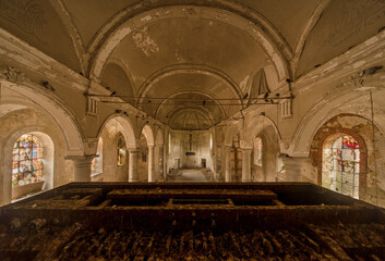 Interior view of an abandoned historic church with peeling paint, stained glass windows, and a...