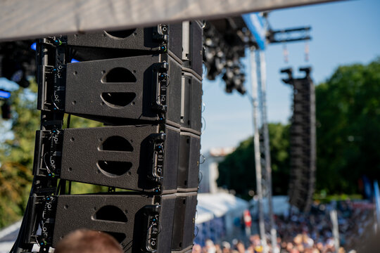 Impressive line array high quality speaker system rigged on stage truss for outdoor music festival with large crowd and vibrant atmosphere