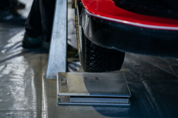 Car wheel being weighed on precision scale during vehicle inspection or motorsport preparation in...