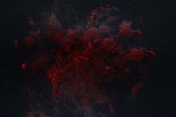 Red textured paint stain on black background as a smear resembling blood for design, horror,...