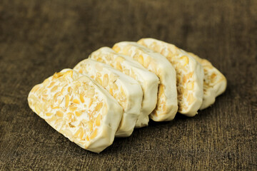 Close-up of tempeh slices on a dark background. Tempeh is a traditional Indonesian side dish made...