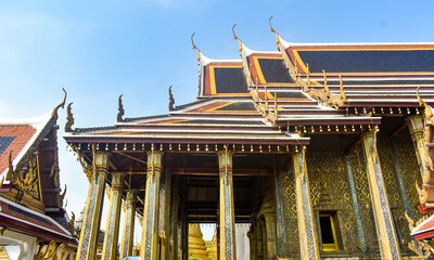 Temple exterior with traditional Thai architecture, golden accents, and ornate roof details. © HB