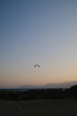 Several kitesurfers ride along the Turkish coastline at sunset. The silhouettes of kites contrast beautifully against the pastel evening sky. Ideal for themes of sport, freedom, beach holidays, and ac