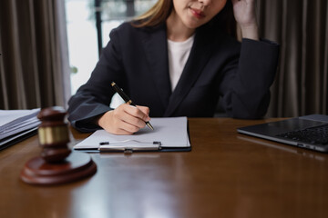 Female lawyer looking stressed while working with laptop and document paper in her office, Law, Justice Symbol,