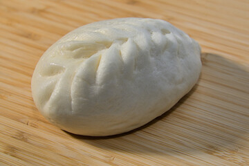 A Steamed Bun Placed on a Bamboo Cutting Board