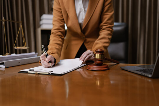 Female Lawyer Working on Document Paper with Writing Signature and Lawyer Hammer at Office Desk, Judge's Gavel, Law, - Powered by Adobe