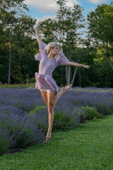 A woman in a flowing lavender dress gracefully leaps above a field of lavender flowers, surrounded...