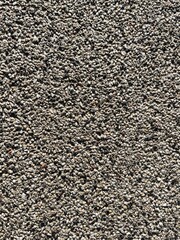 Close-up of an aggregate concrete surface, showcasing a textured pattern of small, embedded pebbles in varying shades of grey and brown.