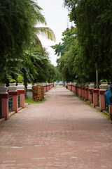 Fototapeta premium A walkway lined with trees and decorative pillars in a garden