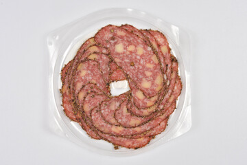 A top-down view shows thinly sliced salami with cheese and peppercorns arranged in a circular pattern against a white background