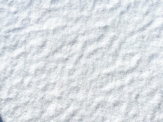 Flat, undisturbed layer of fresh snow with a soft, rippled texture glistening in daylight. Ideal as a clean winter background or seasonal nature detail.