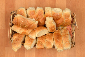 A wicker basket full of freshly baked crescent rolls sprinkled with sesame seeds on a wooden surface
